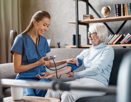 Nurse measuring blood pressure of elderly woman indoors