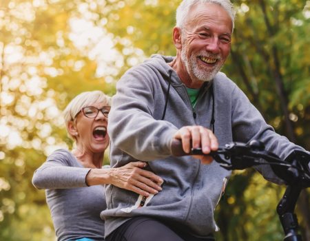 Active senior couple having fun in the park riding on the bicycl