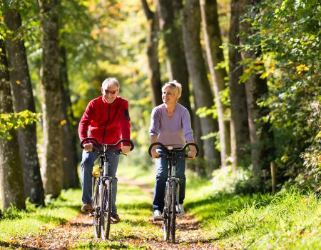 Senior Man and woman exercising with bicycles outdoors, they are a couple
