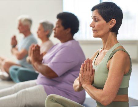 Group of people sitting in lotus position and meditating in yoga class